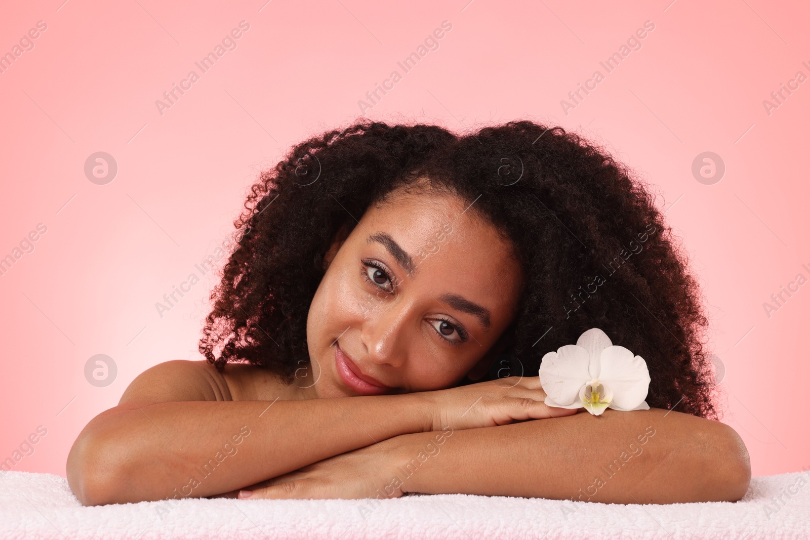 Portrait of beautiful Brazilian woman with orchid flower after spa treatment on pink gradient background Photo of Portrait of beautiful Brazilian woman with orchid flower after spa treatment on pink gradient background