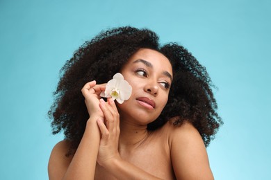 Photo of Portrait of beautiful Brazilian woman with orchid flower after spa treatment on light blue background
