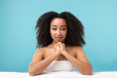 Photo of Portrait of beautiful Brazilian woman with towel after spa treatment on light blue background