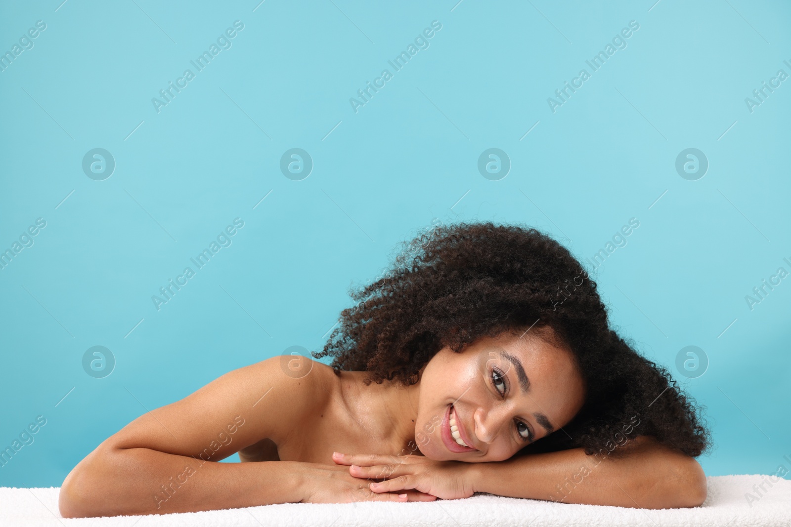 Portrait of beautiful Brazilian woman with towel after spa treatment on light blue background Photo of Portrait of beautiful Brazilian woman with towel after spa treatment on light blue background