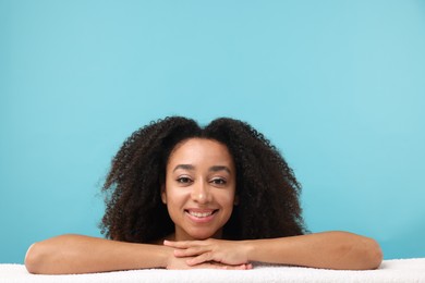 Photo of Portrait of beautiful Brazilian woman with towel after spa treatment on light blue background
