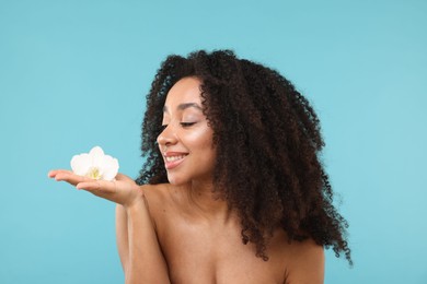 Photo of Portrait of beautiful Brazilian woman with orchid flower after spa treatment on light blue background