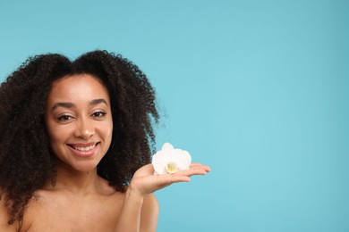 Photo of Portrait of beautiful Brazilian woman with orchid flower after spa treatment on light blue background. Space for text