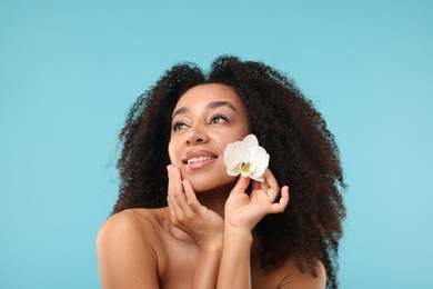 Photo of Portrait of beautiful Brazilian woman with orchid flower after spa treatment on light blue background
