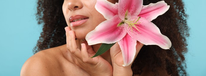 Photo of Brazilian woman with lily flower after spa treatment on light blue background, closeup
