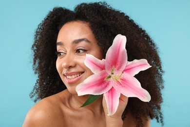 Photo of Portrait of beautiful Brazilian woman with lily flower after spa treatment on light blue background, closeup