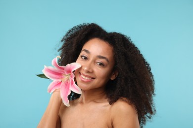 Photo of Portrait of beautiful Brazilian woman with lily flower after spa treatment on light blue background