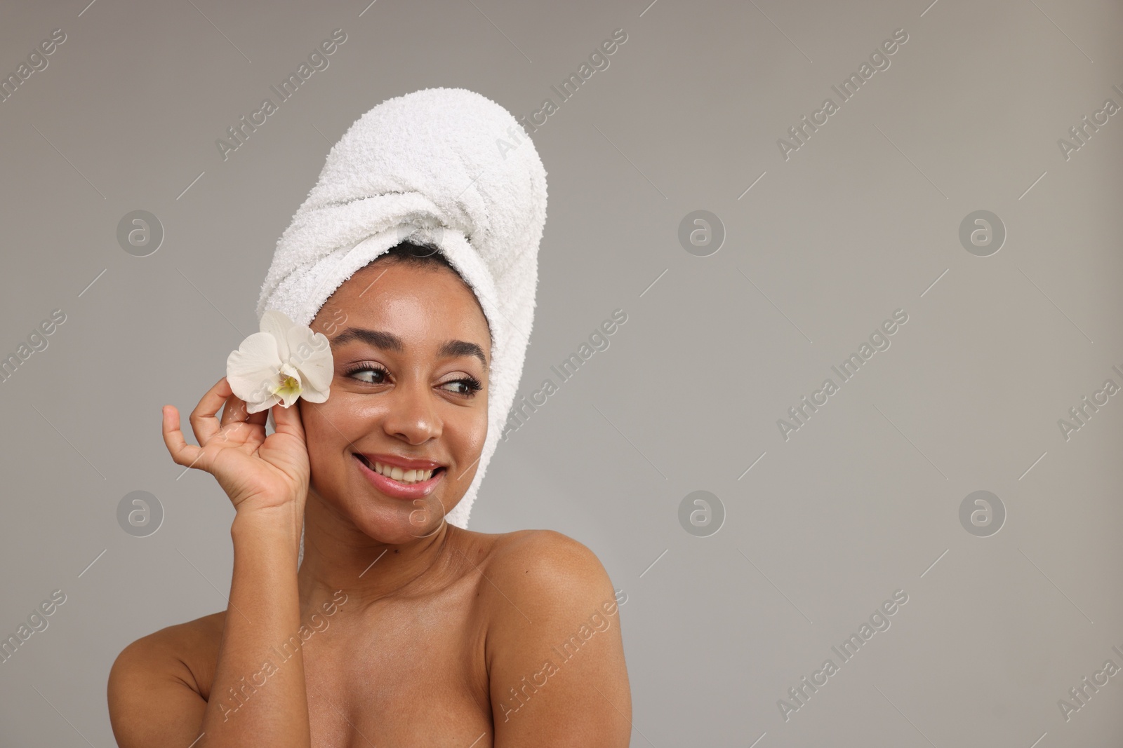 Portrait of beautiful Brazilian woman with orchid flower after spa treatment on gray background. Space for text Photo of Portrait of beautiful Brazilian woman with orchid flower after spa treatment on gray background. Space for text
