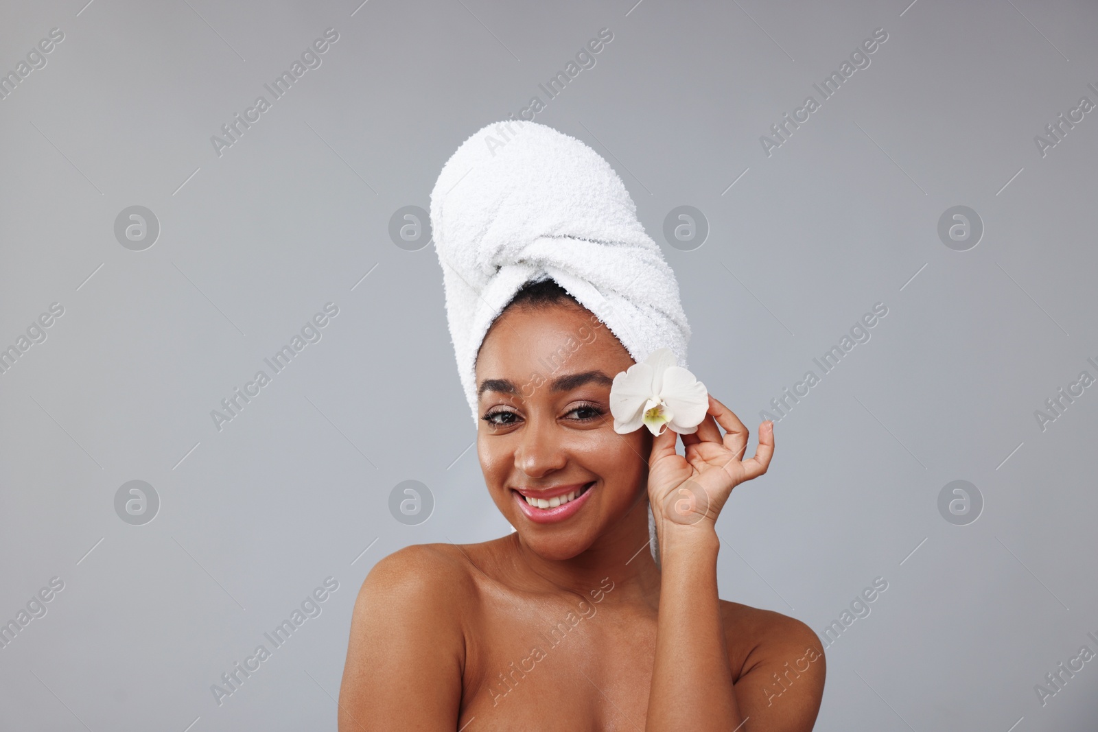 Portrait of beautiful Brazilian woman with orchid flower after spa treatment on gray background Photo of Portrait of beautiful Brazilian woman with orchid flower after spa treatment on gray background