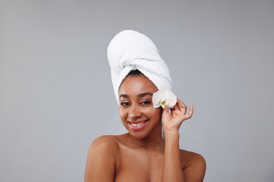 Photo of Portrait of beautiful Brazilian woman with orchid flower after spa treatment on gray background