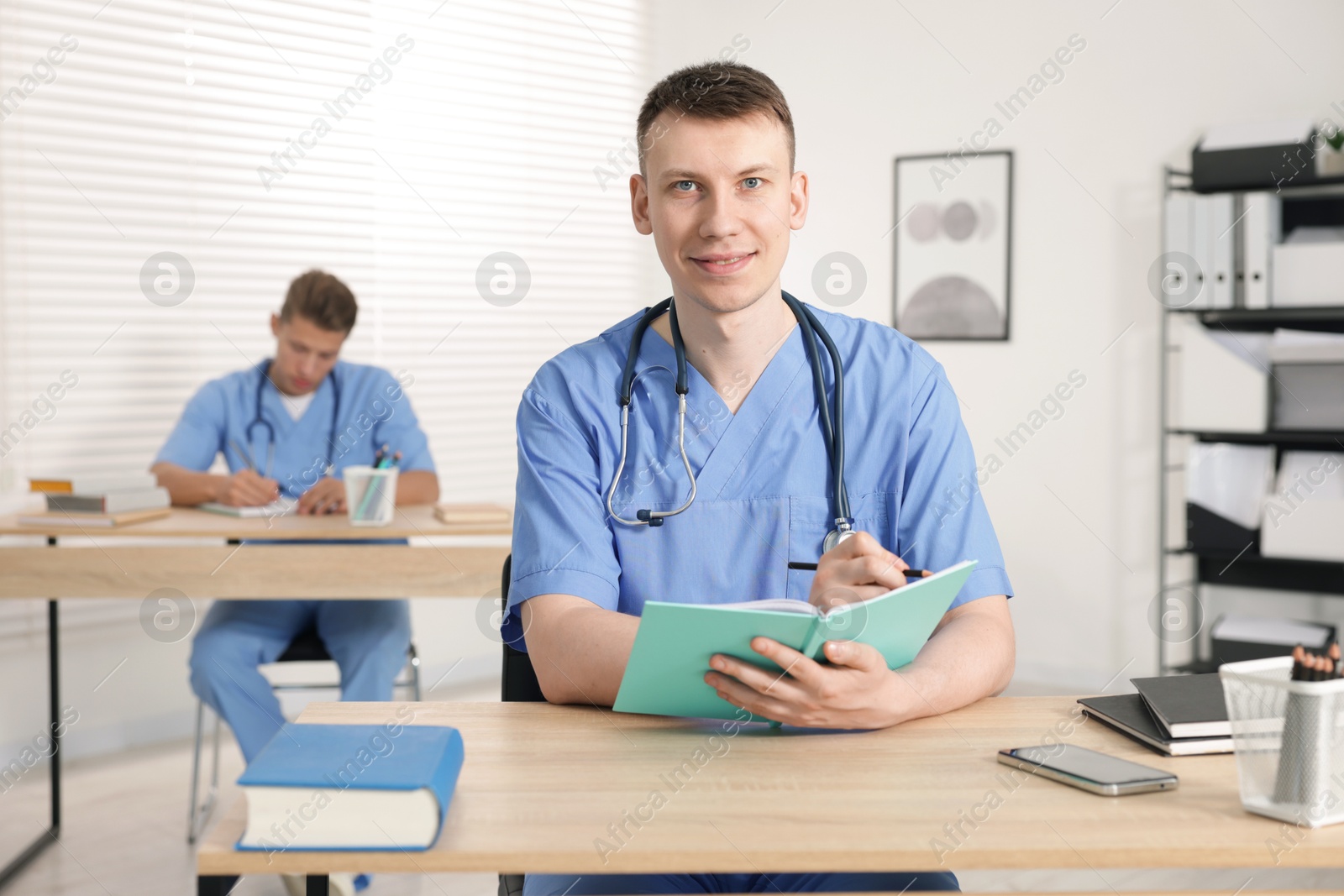 Medical students in uniforms studying at desks indoors, selective focus Photo of Medical students in uniforms studying at desks indoors, selective focus