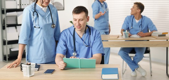 Photo of Medical students in uniforms studying together at university