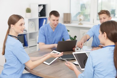 Photo of Medical students in uniforms studying together at table indoors