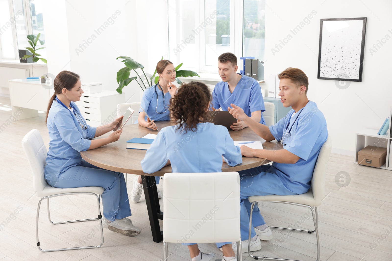 Medical students in uniforms studying together at table indoors Photo of Medical students in uniforms studying together at table indoors