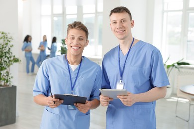 Photo of Medical students in uniforms studying together indoors, selective focus