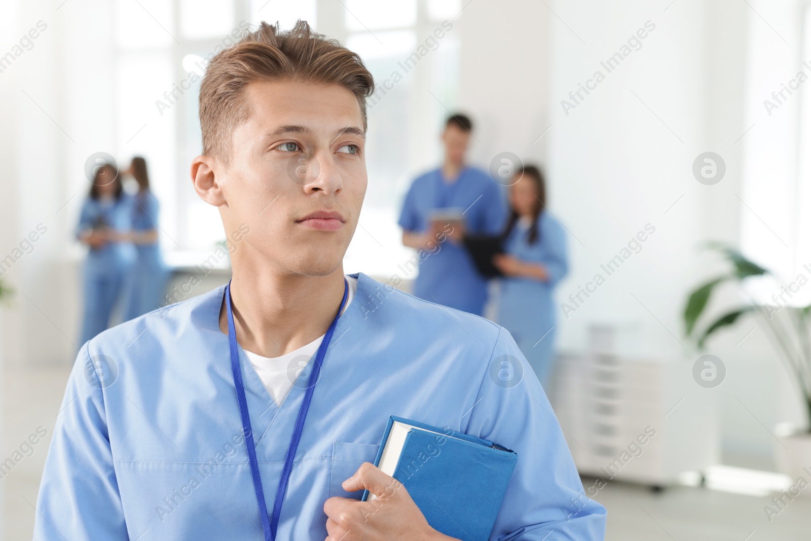 Medical student in uniform with book indoors, selective focus Photo of Medical student in uniform with book indoors, selective focus