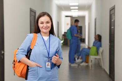 Photo of Medical student in uniform with backpack at university, selective focus