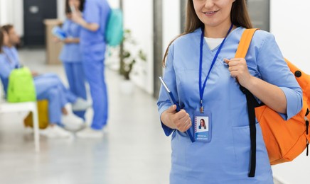Photo of Medical student in uniform with backpack at university, selective focus