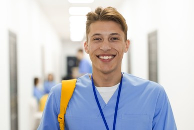 Photo of Medical student in uniform with backpack at university, selective focus