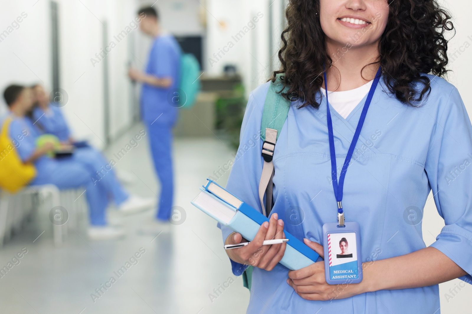 Medical student in uniform with books indoors, selective focus Photo of Medical student in uniform with books indoors, selective focus