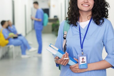 Photo of Medical student in uniform with books indoors, selective focus