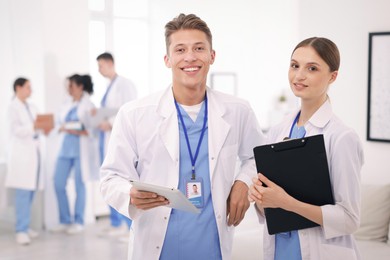 Photo of Medical students in uniforms with tablet and clipboard indoors, selective focus