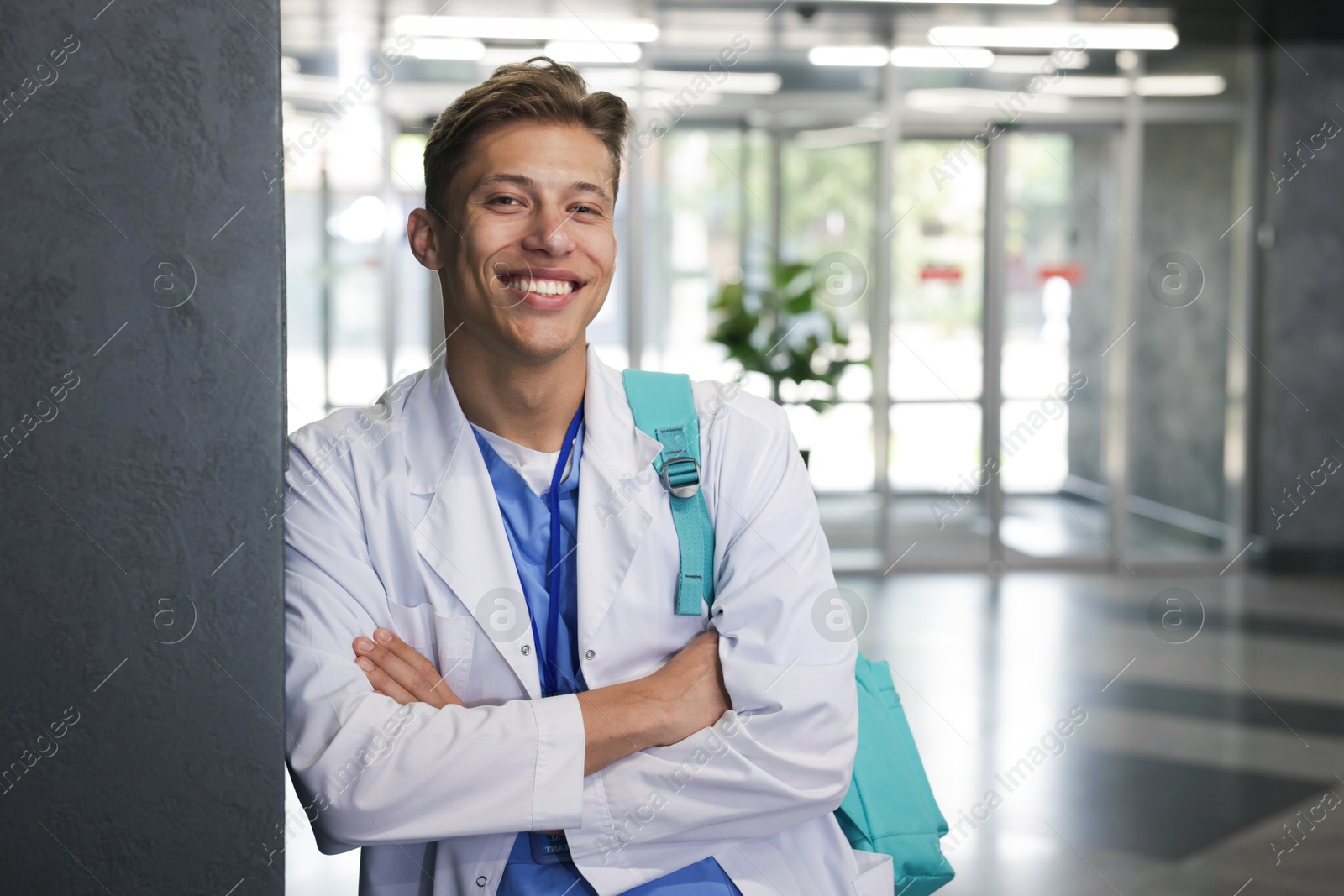 Medical student in uniform with backpack indoors, space for text Photo of Medical student in uniform with backpack indoors, space for text