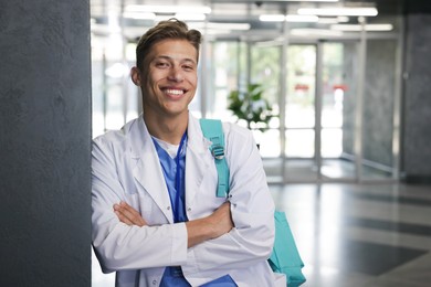 Photo of Medical student in uniform with backpack indoors, space for text