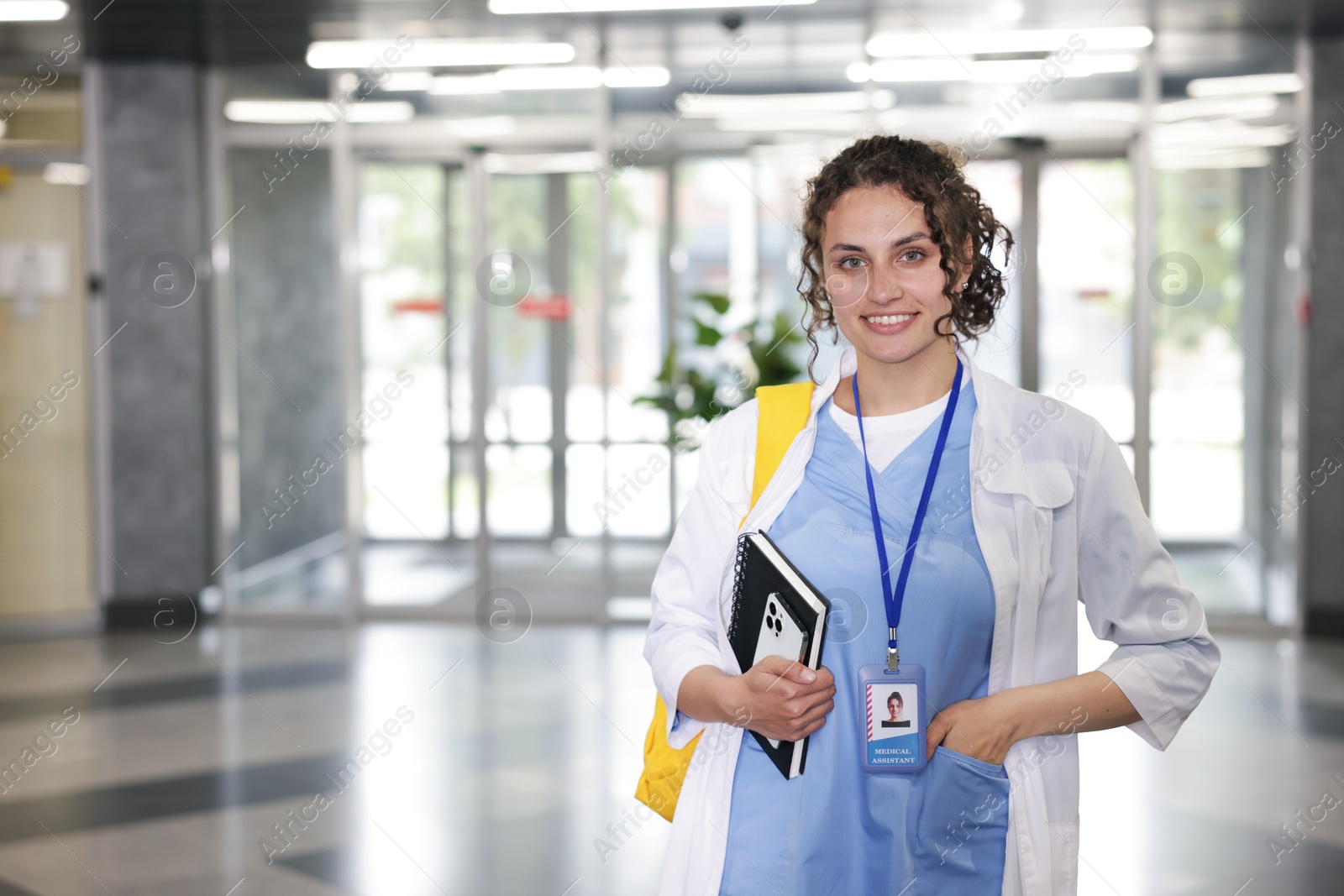 Medical student in uniform with notebook and smartphone indoors, space for text Photo of Medical student in uniform with notebook and smartphone indoors, space for text