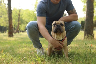 Photo of Man with his cute French bulldog in park, closeup