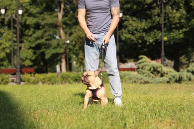 Photo of Man with his cute French bulldog in park, closeup