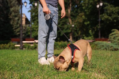 Photo of Man with his cute French bulldog in park, closeup