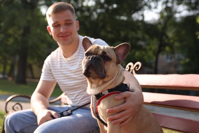 Photo of Happy man with his cute French bulldog on bench in park, selective focus