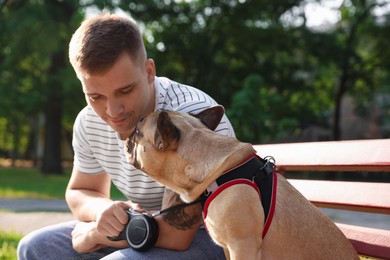 Photo of Happy man with his cute French bulldog on bench in park