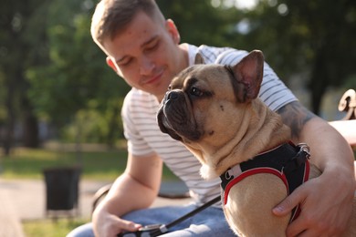 Photo of Happy man with his cute French bulldog on bench in park, selective focus