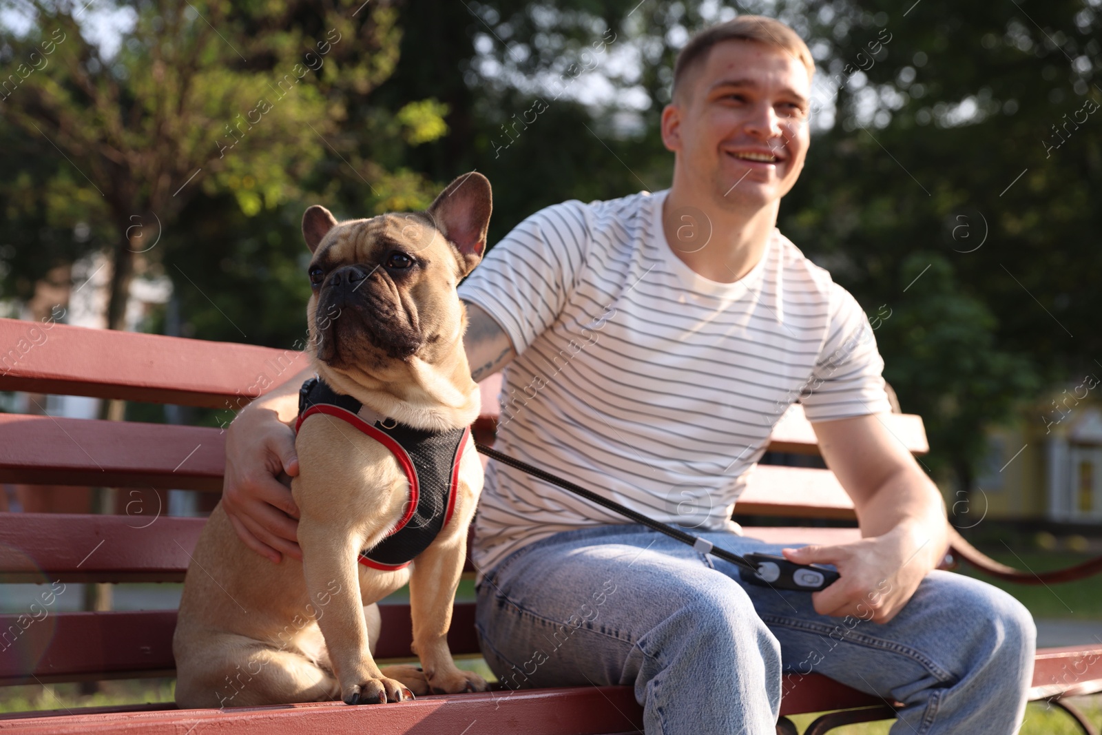 Happy man with his cute French bulldog on bench in park Photo of Happy man with his cute French bulldog on bench in park