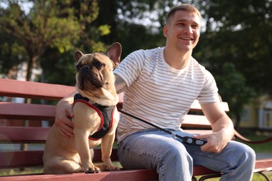 Photo of Happy man with his cute French bulldog on bench in park