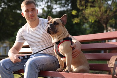 Photo of Happy man with his cute French bulldog on bench in park