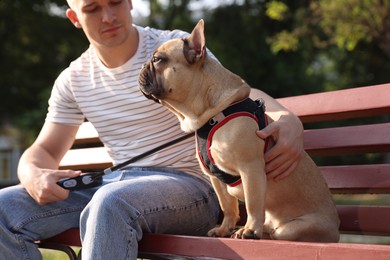 Photo of Happy man with his cute French bulldog on bench in park