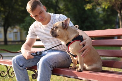 Photo of Happy man with his cute French bulldog on bench in park