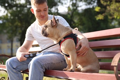 Photo of Happy man with his cute French bulldog on bench in park