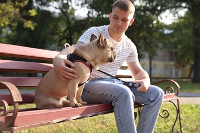 Photo of Happy man with his cute French bulldog on bench in park