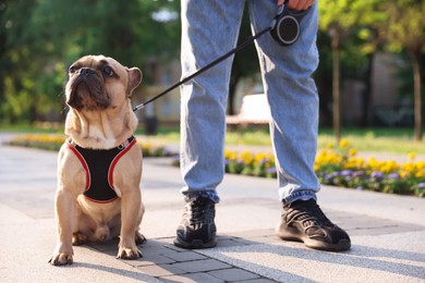 Photo of Man with his cute French bulldog in park, closeup