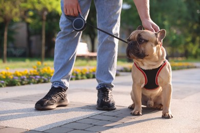 Photo of Man with his cute French bulldog in park, closeup