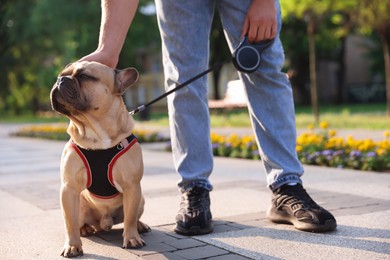 Photo of Man with his cute French bulldog in park, closeup