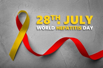Image of 28th july World Hepatitis Day. Yellow-red awareness ribbon on grey textured background, top view
