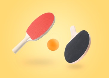 Image of Ping pong rackets and ball in air against pale orange background