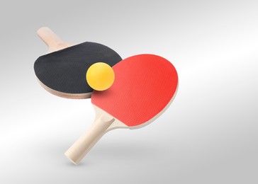Image of Ping pong rackets and ball in air against light grey background