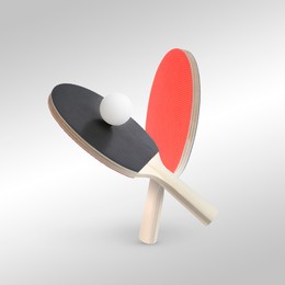 Image of Ping pong rackets and ball in air against light grey background