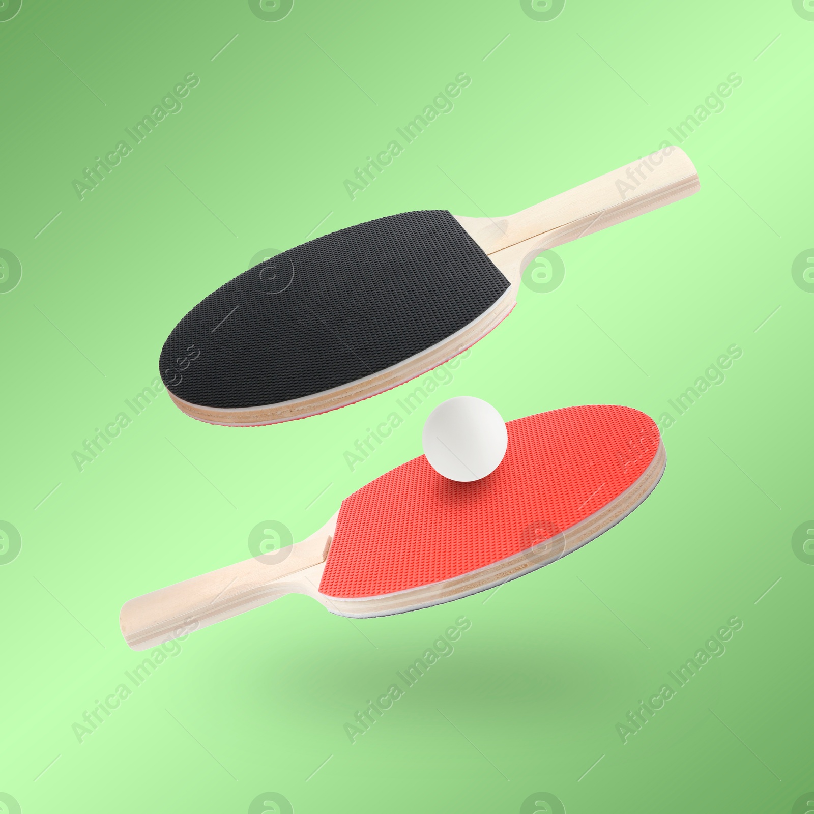 Ping pong rackets and ball in air against light green background Image of Ping pong rackets and ball in air against light green background